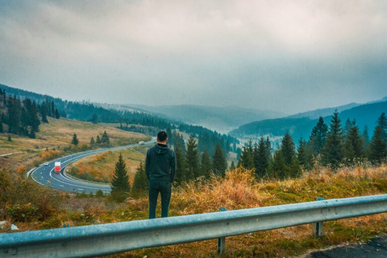 Dieu travaille en silence — Partie 2 1 Un homme se tient au bord d’une route sinueuse et contemple le paysage montagneux.