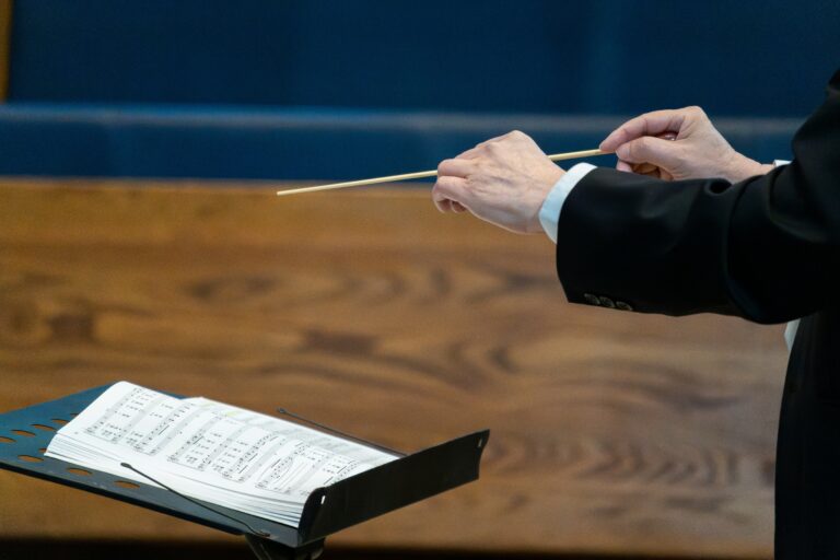 Conductor holding a baton above a musical score